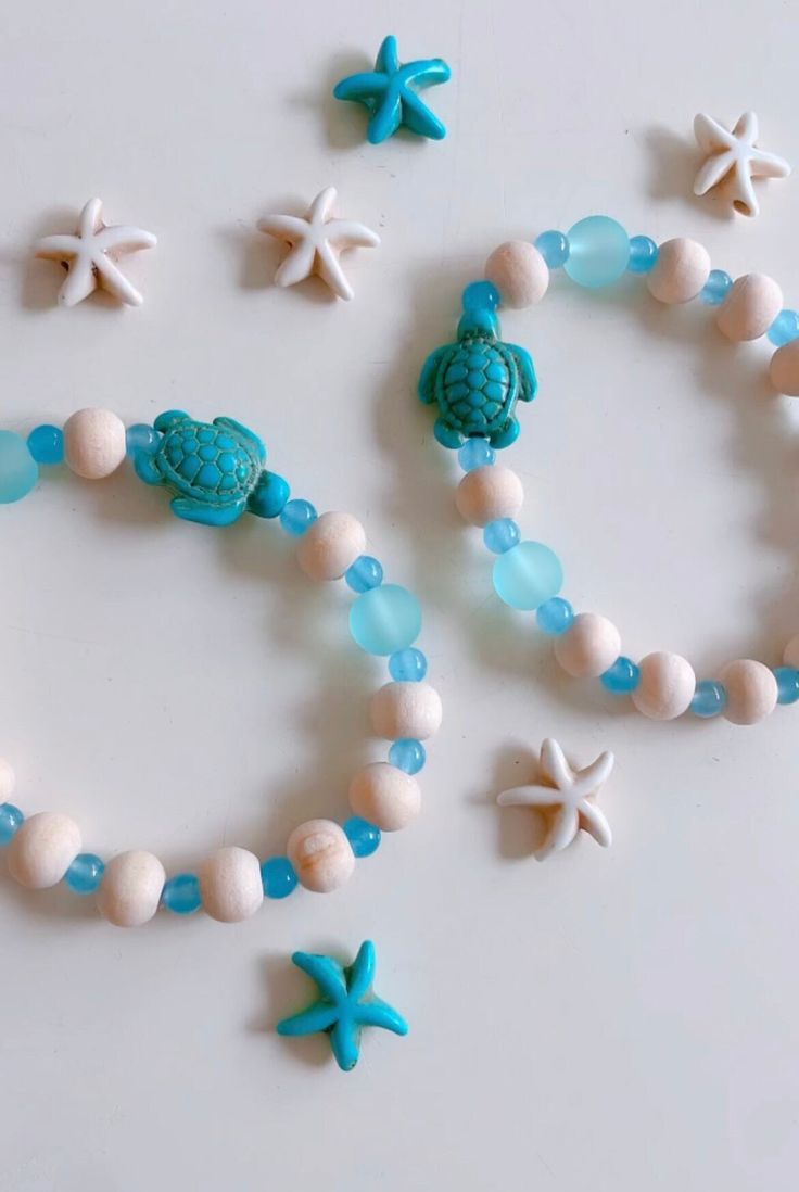 some beads and shells are arranged on a table with starfishs, seashells, and sea urchins