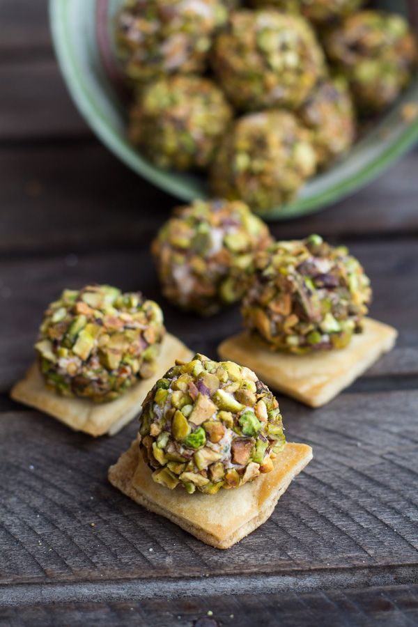 small crackers with pistachios on them sitting next to a bowl of pistachios