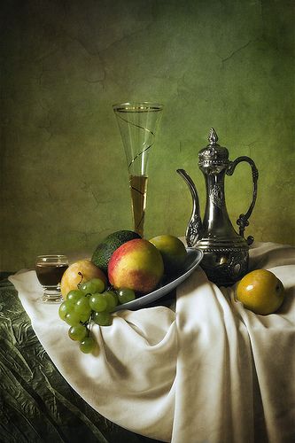 a painting of fruit on a table with a silver teapot and wine glass next to it