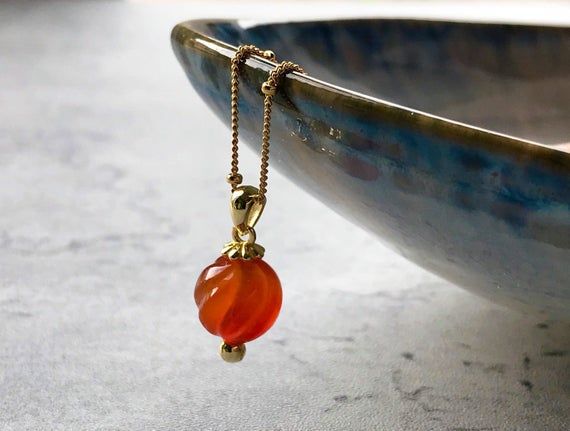 A classic necklace with a contemporary twist, this beautifully vibrant, natural Carnelian gemstone takes centre stage as it’s suspended from an 18” beaded satellite chain. A deep, fiery orange, the captivating Carnelian represents creativity, individuality and courage. It is also the stone of protection, especially from anger, jealousy and fear.Perfect worn alone or layered with other chain necklaces, this eye catching necklace makes a lovely and lasting gift for friends and family, or as a litt Yellow Gold Chalcedony Necklace As Gift, Elegant Faceted Carnelian Necklace, Elegant Carnelian Round Pendant Necklace, Elegant Carnelian Necklace With Polished Finish, Agate Necklace With Polished Finish As A Gift, Agate Necklace With Polished Finish For Gift, Red Carnelian Necklace With Polished Finish, Red Faceted Carnelian Necklaces, Red Carnelian Polished Necklace