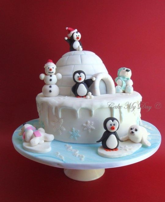 there is a cake decorated with penguins and snowmen on the top of it, as well as an igloose