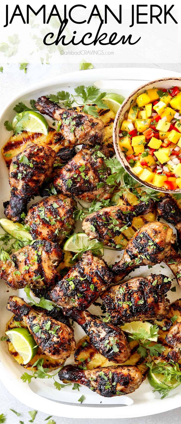 grilled chicken and vegetables on a white platter with a bowl of mango salsa