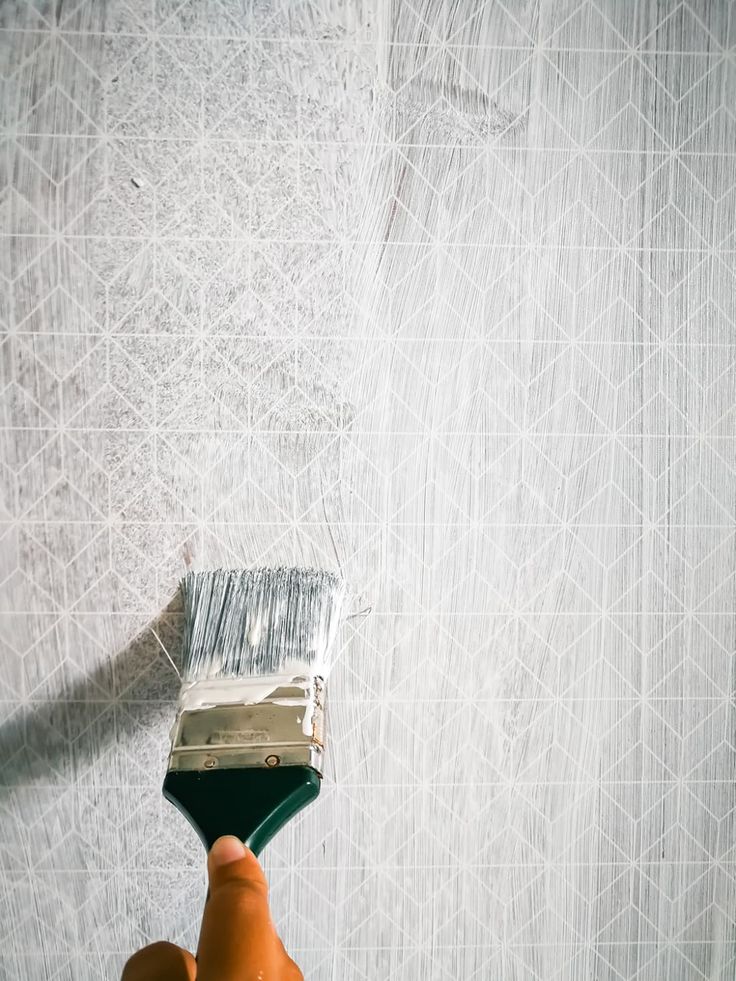 a person holding a paint brush in front of a wall with white lines on it