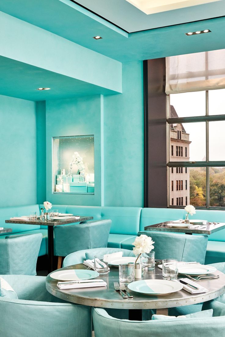 a dining room with blue walls and white tablecloths on the tables in front of large windows