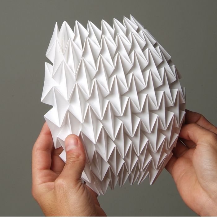 two hands holding an origami ball in front of a gray background with the words how to make paper balls