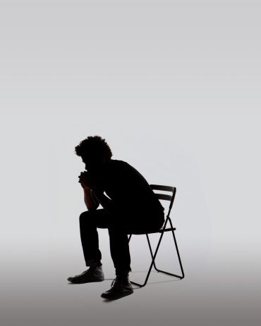 the silhouette of a man sitting in a chair with his hand on his chin, against a white background