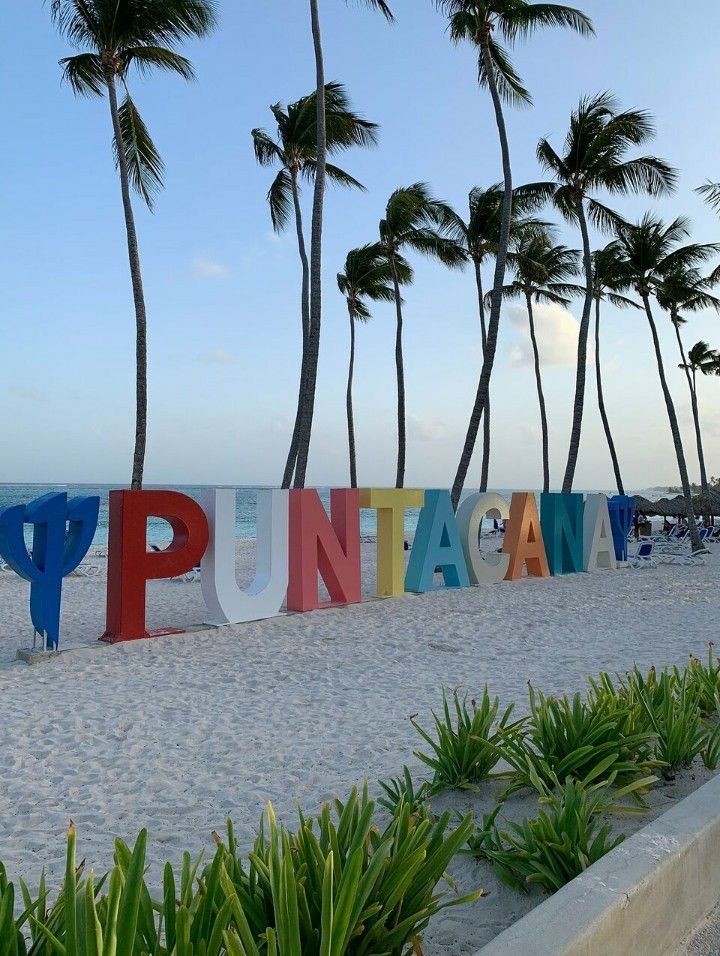 the word puntawn is written in multicolored letters on a sandy beach with palm trees