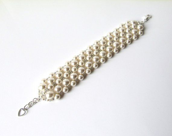 A timeless bracelet completely hand-woven in your choice of Swarovski white (shown in pictures) or ivory/cream pearls and tiny antique silver Japanese seed beads. ~1/2 INCH EXTENSION INCLUDED ~ For adjustable sizing, embellished with silver heart charm~Width Approximately 1.25 inches~♥ All jewelry comes in a gift box and is ready to give, at no additional cost! ♥------::BRACELET SIZE::X Small - 6.5" ~ expands toSmall - 7" ~ expands to 7.5"Standard - 7.5" ~ expands to 8"Large - 8" ~ expands to 8. White Pearl Beaded Bracelet For Wedding, Handmade Adjustable Pearl Bracelet For Wedding, Adjustable Cream Bracelet For Wedding, Adjustable Cream Bracelet For Weddings, Classic Handmade Wedding Bracelets, Handmade Classic Wedding Bracelets, Cream Wedding Bracelet Jewelry, Formal White Adjustable Beaded Bracelets, White Adjustable Beaded Bracelets For Formal Occasions