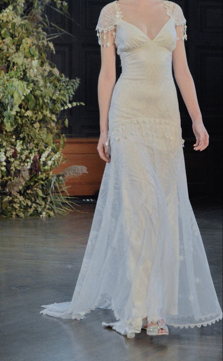 a woman in a white dress walking down a runway