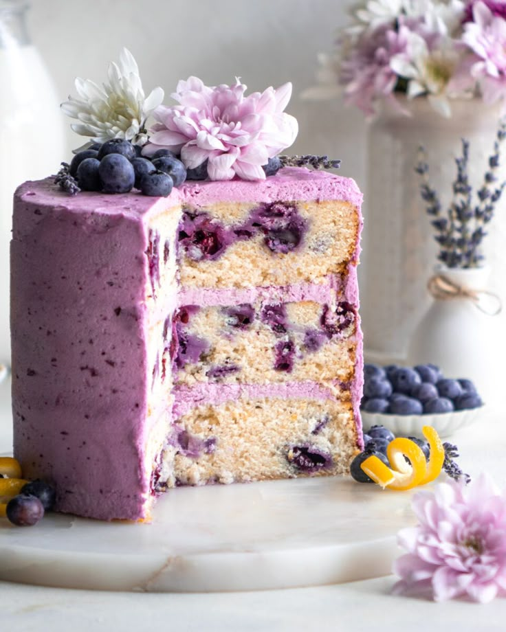 there is a cake with blueberries and flowers on the top it's cut in half