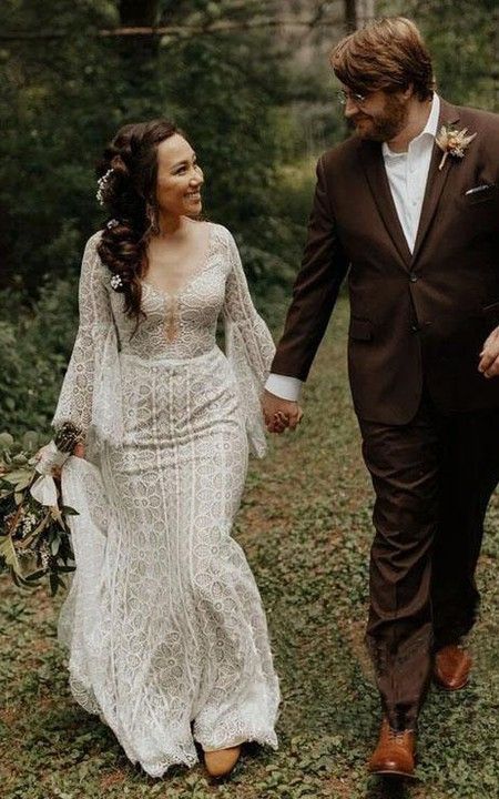 a bride and groom are walking through the woods holding each other's hands as they walk hand in hand