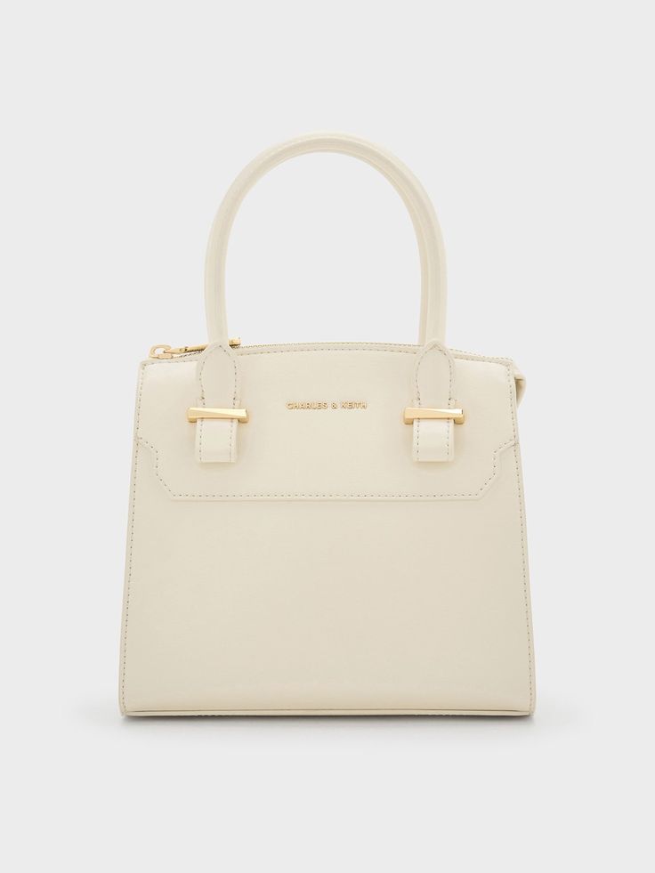 The Temmie structured tote bag is designed to take you from day to night. In soft cream, this bag is perfect for those who love a clean and structured white bag. It opens up to a spacious main compartment that features a back zip pocket and inner flap pocket that will help to keep your belongings organised. The gold-tone hardware adds luxurious shine and a sophisticated touch. It also comes with a detachable strap that let yo carry it in multiple ways. Classic Cream Tote Box Bag, Cream Box Bag With Detachable Handle, Chic Cream Box Bag With Double Handle, Cream Satchel Box Bag With Detachable Handle, Cream Box Bag For Everyday Use, Classic Cream Box Bag With Detachable Handle, Modern Cream Box Bag With Detachable Handle, Cream Satchel Box Bag, Classic Daily Top Handle Satchel