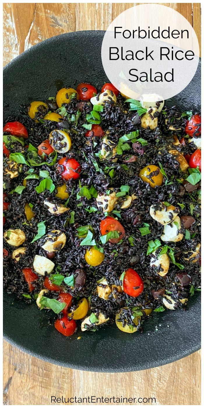 black rice salad with tomatoes, mushrooms and herbs in a skillet on a wooden table