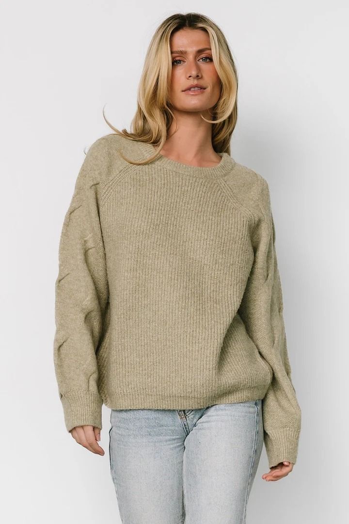 a woman wearing a beige sweater and jeans