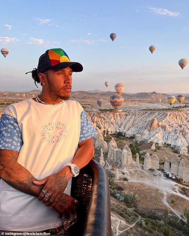 a man standing on top of a balcony next to hot air balloons