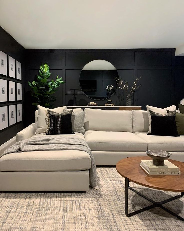 a living room with black walls and white couches, coffee table and pictures on the wall