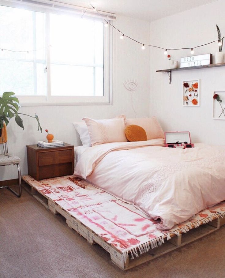 a bed sitting in a bedroom next to a window with string lights hanging above it