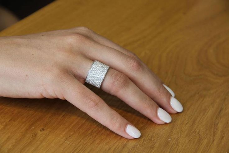 a woman's hand with a ring on top of a wooden table next to a computer keyboard