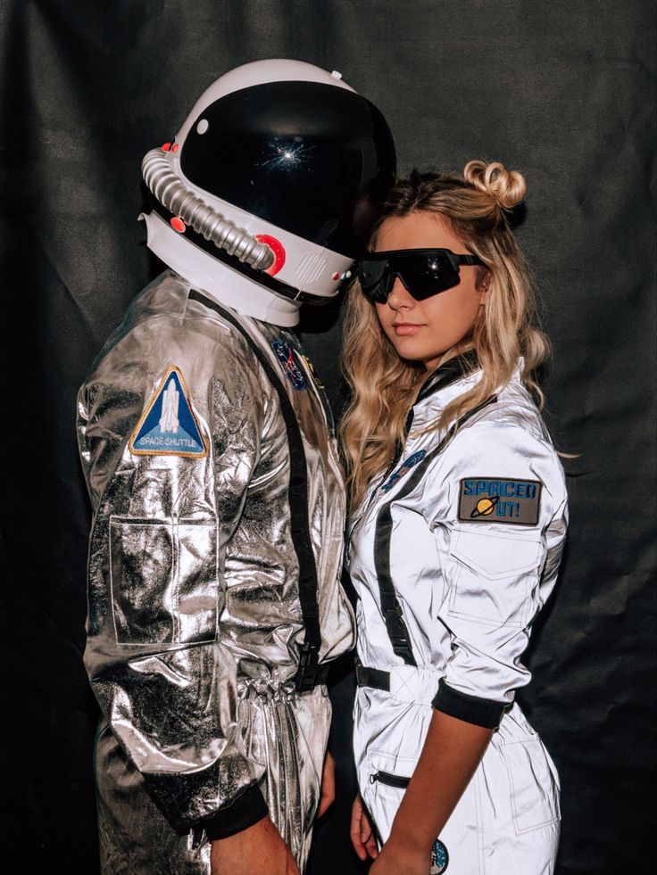 two people dressed up as astronauts posing for a photo together in front of a black background