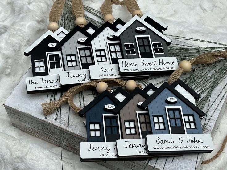 three wooden houses with name tags attached to them sitting on top of a white blanket