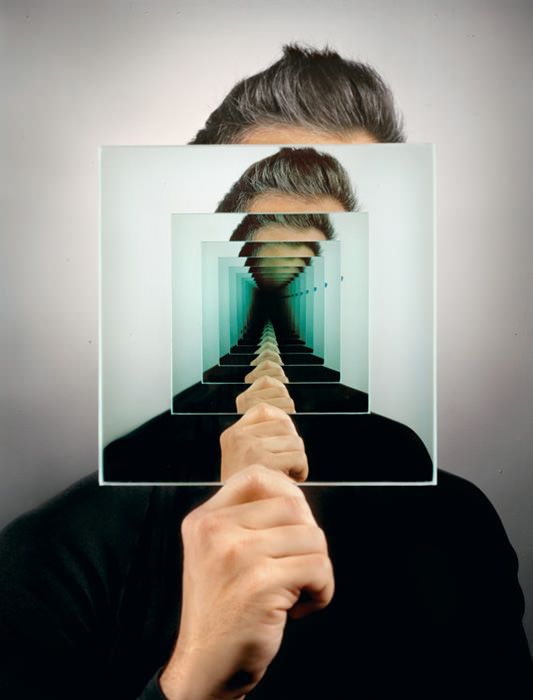 a man holding up a mirror with his face in front of him