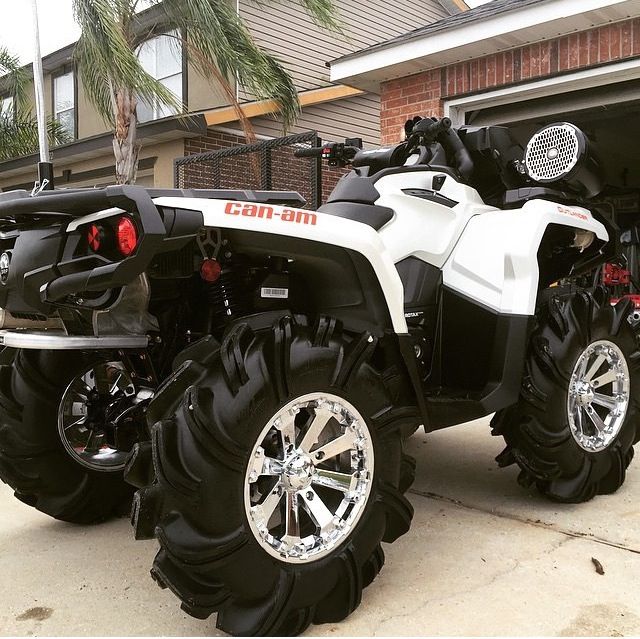 a white four - wheeler parked in front of a house with large tires on it