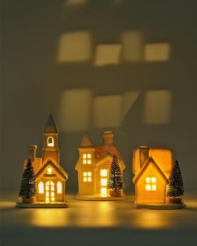 three small houses are lit up with christmas lights in front of the windows and shadows on the wall