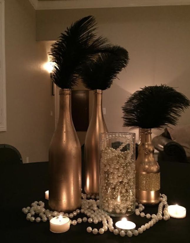 three vases with feathers and candles on a table