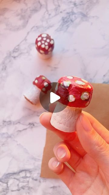 a person is holding a small mushroom with polka dots on it, and another mushroom has been made out of wood