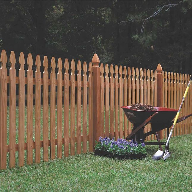 a wheelbarrow in the grass near a wooden fence