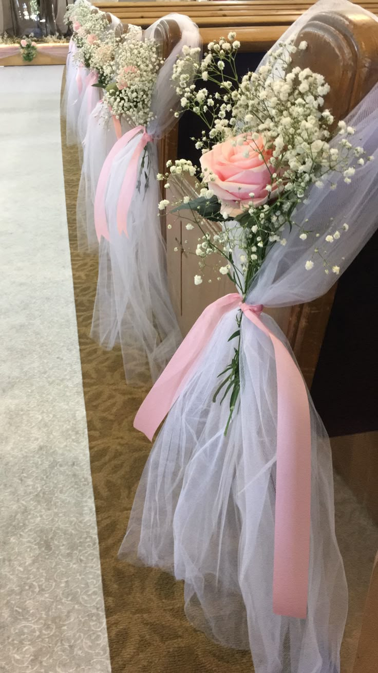 flowers are tied to the pews at a wedding ceremony with tulle and pink ribbon