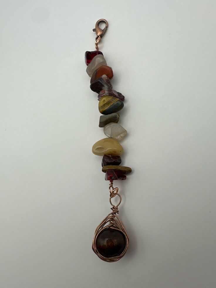 a necklace with several different colored stones hanging from it's side on a white surface