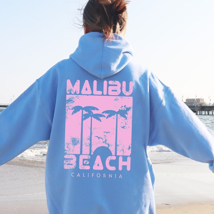 Embrace the laid-back vibes of Malibu with our Malibu Beach Hoodie. This soft blue sweatshirt features a stylish, vintage-inspired Malibu Beach print. The design showcases palm trees with a sunset beach scene, bringing a touch of tropical paradise to your everyday wear. This hoodie is perfect for beach lovers, travelers, and anyone who loves to stay cozy while looking effortlessly cool. The classic fit suits both men and women, ensuring maximum comfort and style. WHY YOU'LL LOVE IT ✅ Comfy: This Beach Season Cotton Hooded Sweatshirt, Casual Letter Print Hoodie For Beachwear, Casual Beach Hoodie Top, Casual Beach Season Hoodie Tops, Casual Hoodie Tops For Beach Season, Cotton Hooded Sweatshirt For Beach Season, Hooded Cotton Sweatshirt For Beach Season, Casual Surfing Hoodie Sweatshirt, Blue Hooded Beach Tops