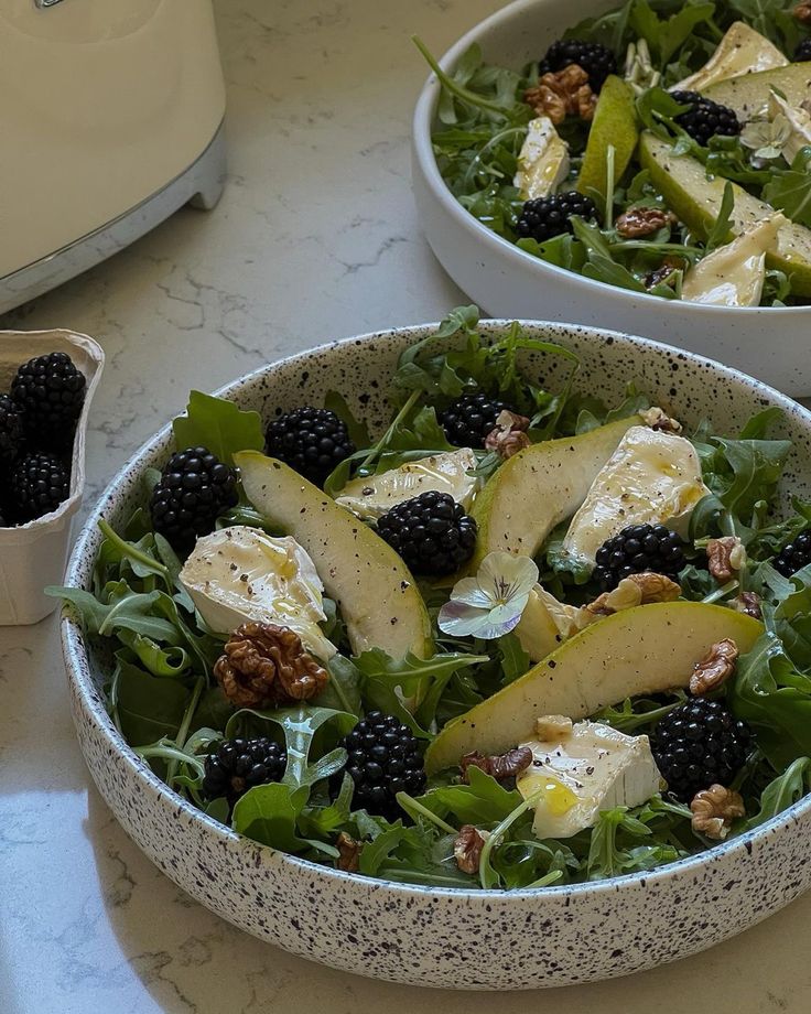 two bowls filled with fruit and cheese on top of a table