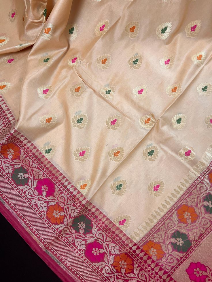 Gorgeous Ivory Cream / Light Gold Silk Saree with Grand Pallu. Floral designs on Hot Pink Pallu. Blouse pieces is Hot Pink matching the Pallu with tassels adding to the beauty of the Saree. The Border are Rose Pink in color. A complete designer wear Saree. Item : SareeBase Fabric : Banarasi SilkColor : Ivory Cream with Pink Blouse piece : Comes with un-stitched Blouse piece.Blouse material : Banarasi SilkWork : Woven, Zari Weaved, Meenakari Work Fall & Edging (Yes/No) : Yes Disclaimer :-- Color Beige Cutdana Dupatta For Navratri, Cream Dupatta For Navratri With Traditional Drape, Traditional Cream Dupatta For Navratri, Cream Dola Silk Dupatta With Cutdana, Festive Cream Saree With Zari Work, Traditional Cream Saree With Dupatta, Cream Saree With Dupatta In Traditional Drape, Cream Dola Silk Traditional Wear With Zari Work, Cream Dola Silk Saree With Traditional Drape