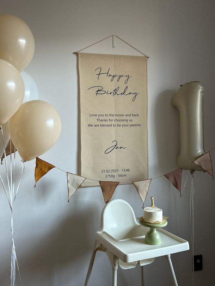 a birthday banner hanging on the wall next to balloons and a table with a cake