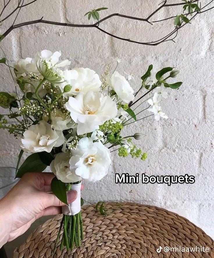 a person holding a bouquet of white flowers in front of a basket on the floor