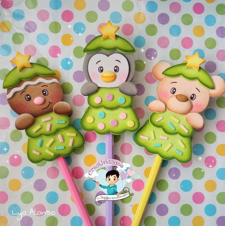 three decorated cookies are sitting on top of each other with pencils in front of them