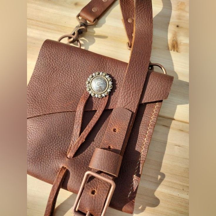 Artisan Made Wells Leather City Bag, Brown Oil Tanned Leather Crossbody With Silver Concho And Leather Lasso Closure Copper Hardware, Back Pocket Holds Cell Phone, Id. Lipstick Etc..Bag Measures 7” H X 7.””W Adjustable Strap. Strap Can Be Adjusted From 52” To 56” Length. Custom Colors And Orders Welcome. Boho Festival Western Moto Motorcycle Hippie Cowgirl Artisan Leather Crossbody Satchel, Everyday Leather Belt Bag With Leather Strap, Leather Belt Bag With Leather Strap For Daily Use, Handmade Leather Pouch Belt Bag, Artisan Leather Shoulder Bag For Everyday, Handmade Leather Pouch Saddle Bag, Handmade Leather Saddle Bag Pouch, Leather Belt Bag With Leather Lining, Hand Tooled Leather Pouch Satchel