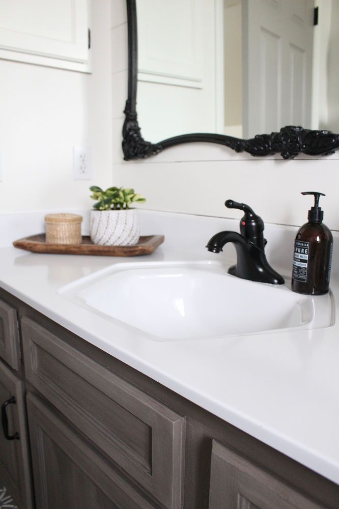 a bathroom sink sitting under a mirror next to a wooden tray with soap and toothbrushes