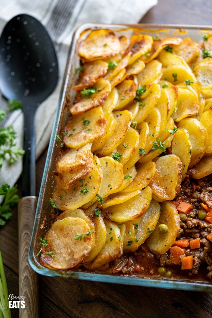 a casserole dish with potatoes, meat and carrots on the side is ready to be eaten