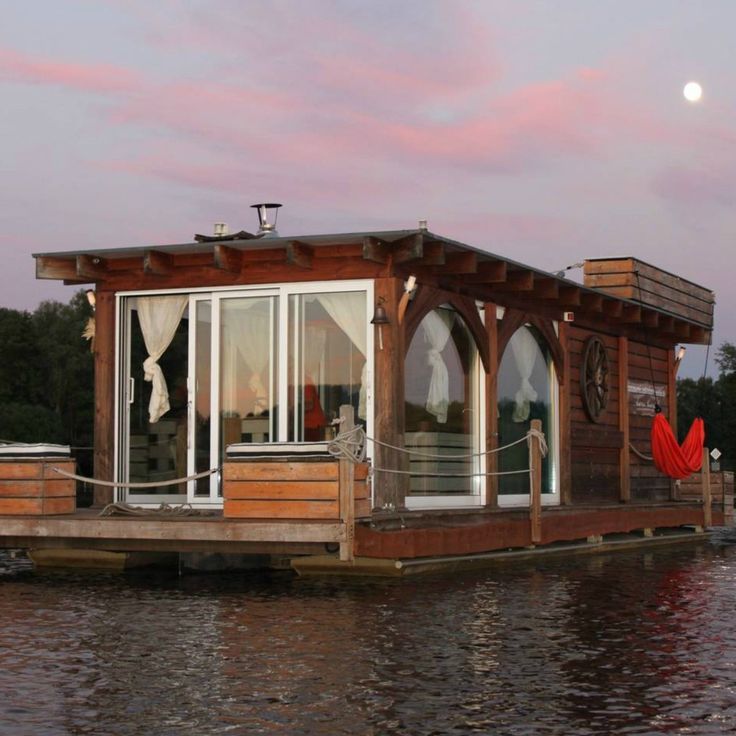 a houseboat floating on top of a body of water under a pink sunset sky