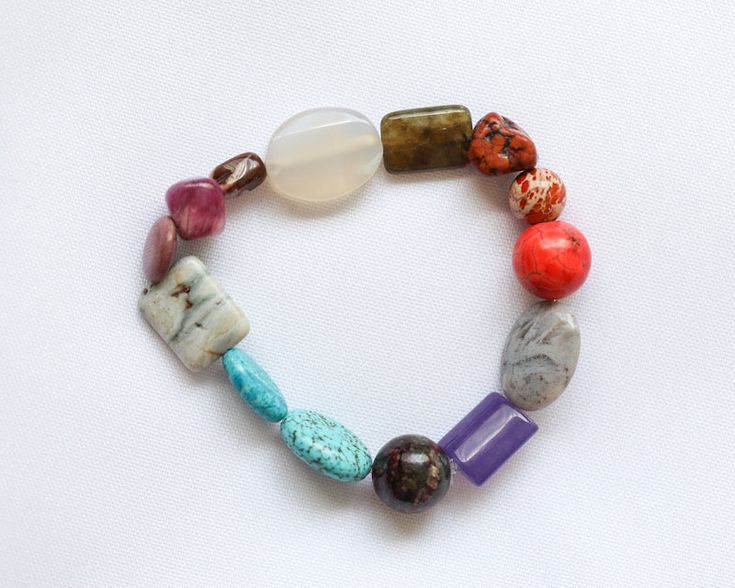 Colorful assorted gemstone bracelet, laying on lightly textured white fabric. Bracelet Stands, Ruby Zoisite, Gemstone Bracelet, Gemstone Beads, Agate, Ruby, Amethyst, Beaded Bracelets, Turquoise