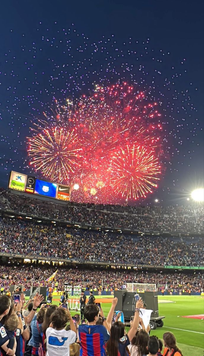 fireworks are lit up in the sky above a baseball field as spectators watch from the stands