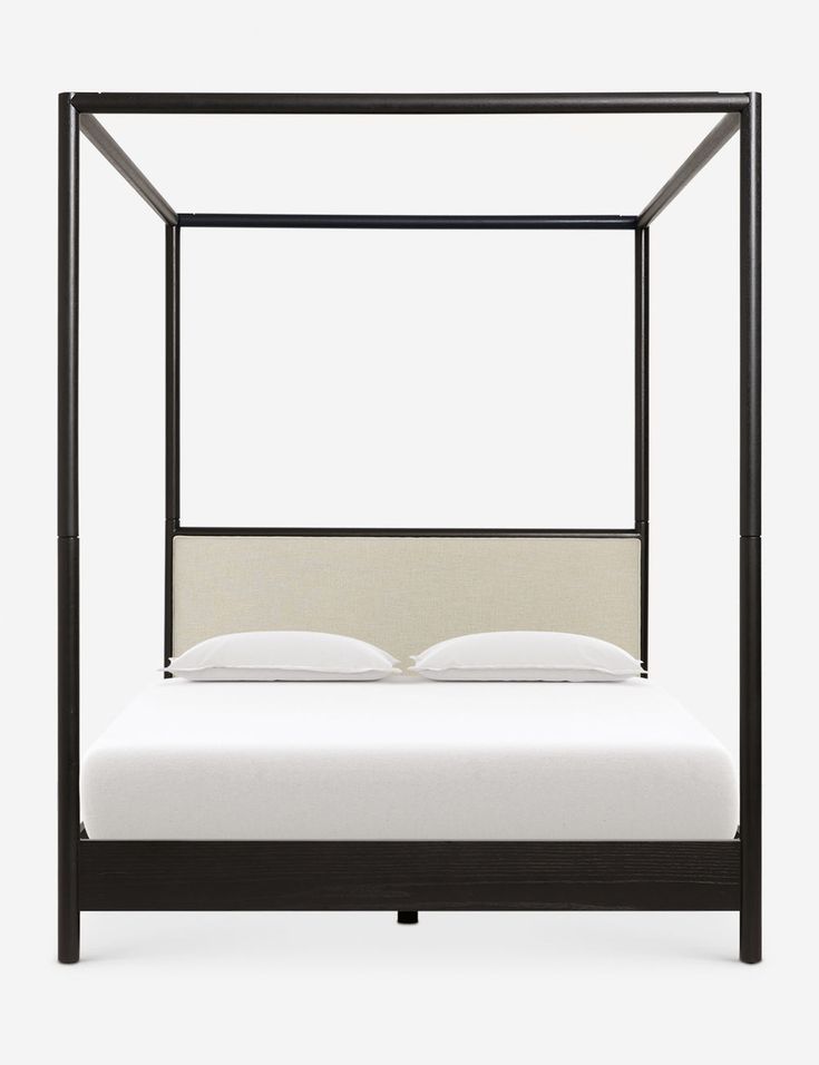 an iron bed frame with white sheets and pillows on the bottom, in front of a gray background