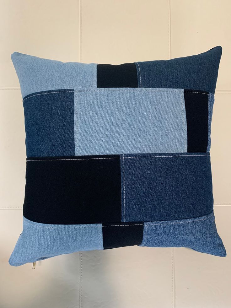 a blue and black patchwork pillow hanging on a wall