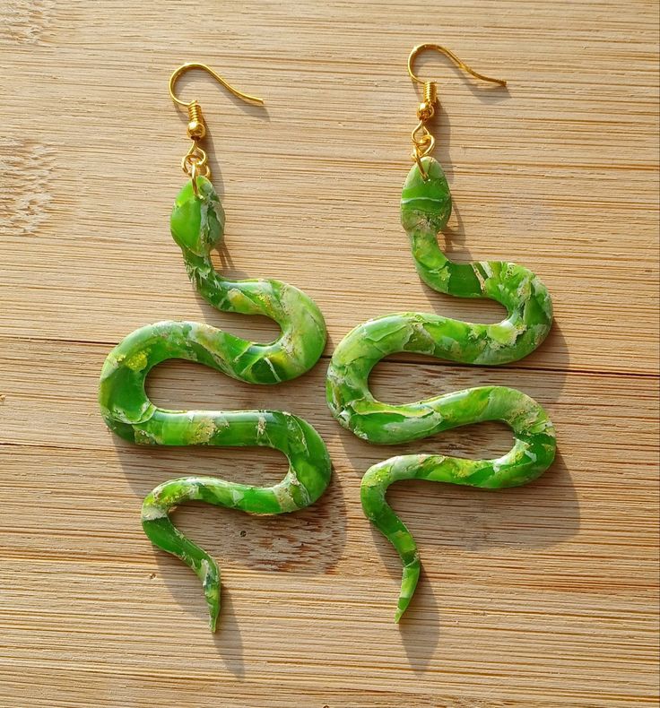 These snake earrings are made of polymer clay and are very lightweight. The green will let the light come though which gives it a beautiful glass like finish. Handmade Nature-inspired Resin Earrings, Whimsical Green Jewelry For Gifts, Nature-inspired Handmade Resin Earrings, Whimsical Green Hand Painted Earrings, Green Hand Painted Drop Earrings, Handmade Green Whimsical Earrings, Green Bohemian Polymer Clay Jewelry, Snake-shaped Earrings With Ear Wire For Gift, Snake-shaped Earrings With Ear Wire As Gift