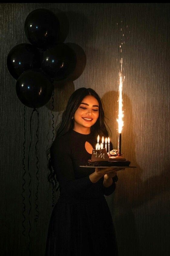 a woman holding a cake with lit candles