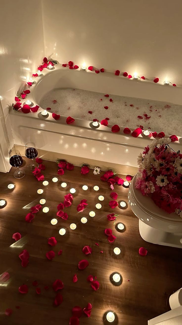 a bathtub with candles and flowers on the floor next to it is lit up