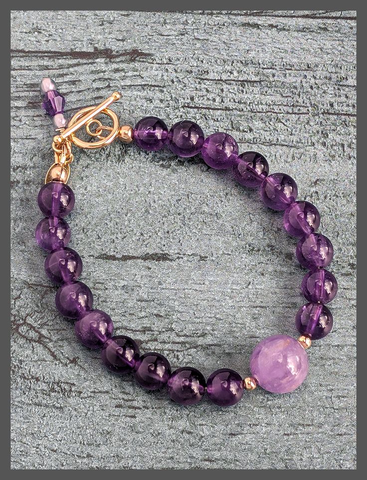 Introducing our Amethyst and Gold Bracelet with a 14K Gold-Filled Toggle Clasp. This exquisite piece combines the captivating beauty of amethyst gemstones with the timeless elegance of gold. The bracelet features amethyst beads and a secure, stylish toggle clasp along with the artist tag and amethyst charm. Elevate your style with this versatile accessory that can be worn alone or layered with other bracelets. The Bracelet measures 7.5" Visit the Amethyst Collection Here Elegant Amethyst Bracelet, Classic Amethyst Bracelets, Elegant Amethyst Gemstone Bracelets, Classic Purple Bracelet Jewelry, Classic Purple Round Bead Jewelry, Timeless Amethyst Jewelry, Elegant Lavender Amethyst Bracelets, Elegant Lavender Amethyst Bracelet, Yellow Gold Amethyst Gemstone Beads Jewelry